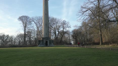 Low-angle-aerial-view-pull-back-across-Ashridge-estate-Bridgewater-monument-and-National-trust-autumnal-woodland-landscape