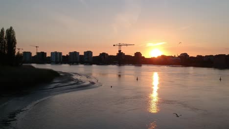 city buildings and construction cranes during golden sunset, aerial fly forward