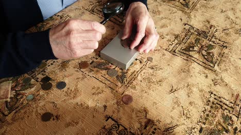 coin evaluator. the collector of coins. the man considers ancient coins.