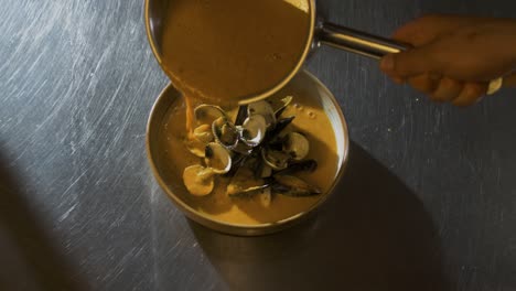 chef pours sauce on shellfish foodplate