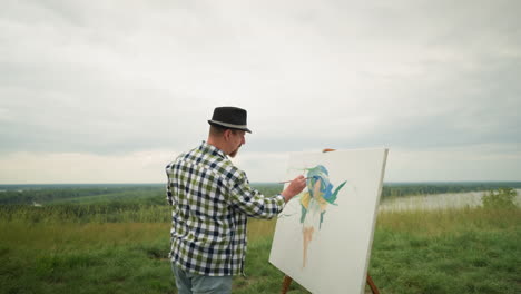 an artist, wearing a hat, checkered shirt, and jeans, is deeply focused on painting on a board in the middle of a lush grassy field under a cloudy sky