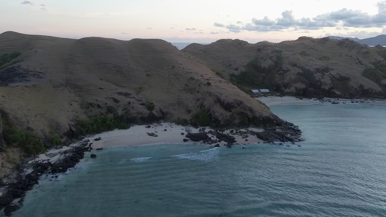 Cinematic aerial of Bukit Merese, Indonesia, revealing a tropical coastline and hills at sunset. Ideal for tourism campaigns, travel films, and lifestyle video content