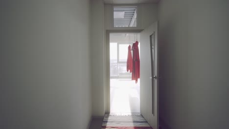 open door to a modern yoga or fitness studio with red hanging clothes