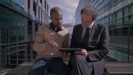 professional managers using digital tablet on meeting near office building