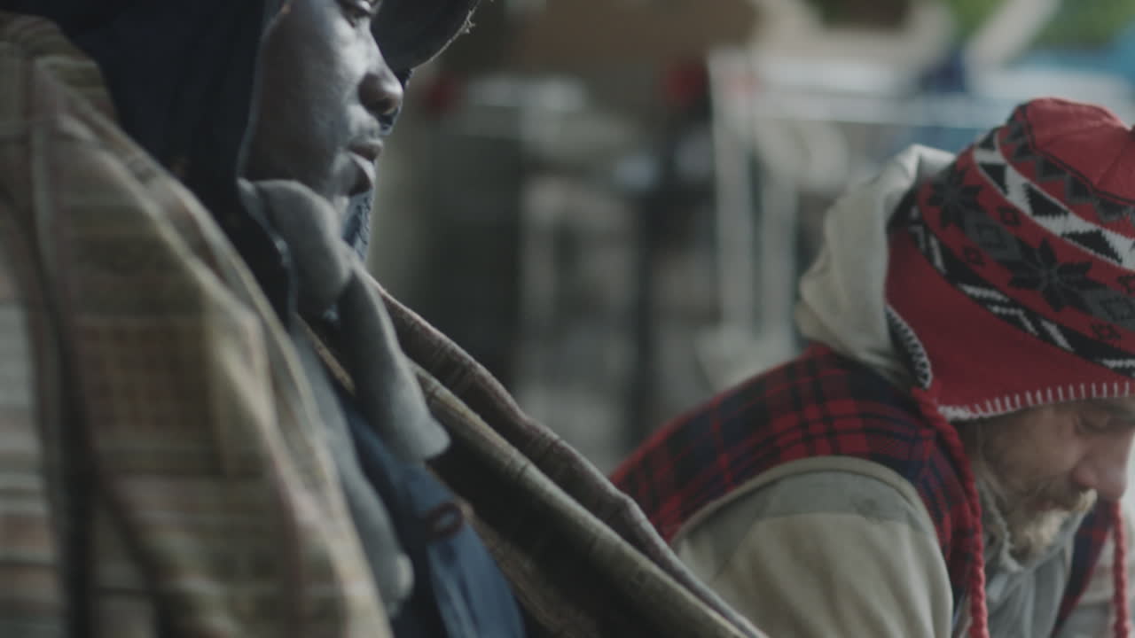Two homeless men enduring the elements on a city street