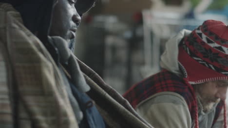 two homeless men enduring the elements on a city street