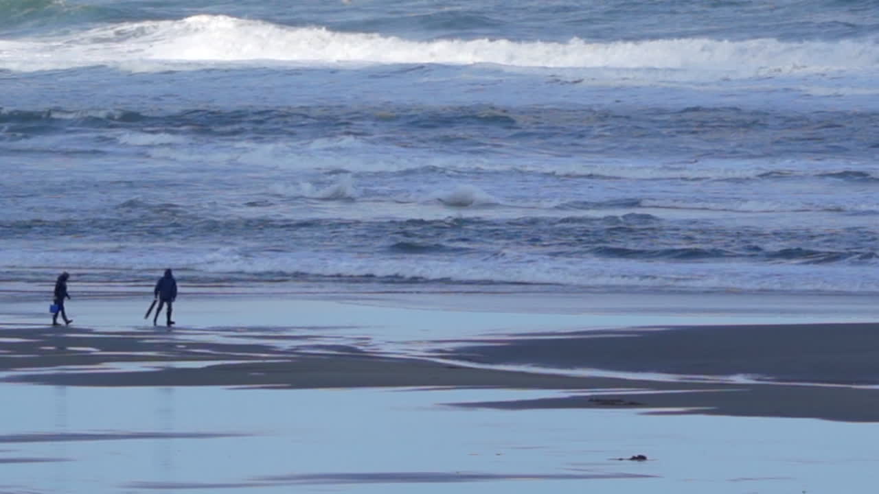 오레곤 해변에서 서핑을 따라 걷는 사람들