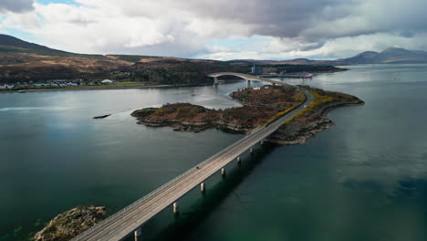 wide angle overview of skye bridge scotland, calm waters reflect cloudy sky above