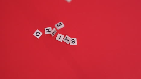 White-letter-tiles-moving-to-spell-out-christmas-on-red-background