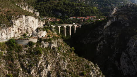 avanço aéreo mostrando estradas na montanha e ponte gigantesca com condução de veículos em segundo plano durante o dia ensolarado