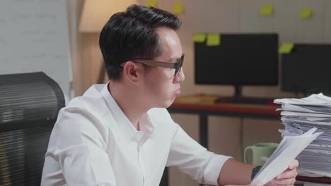 문서와 함께 열심히 일하는 피곤한 아시아인 남자