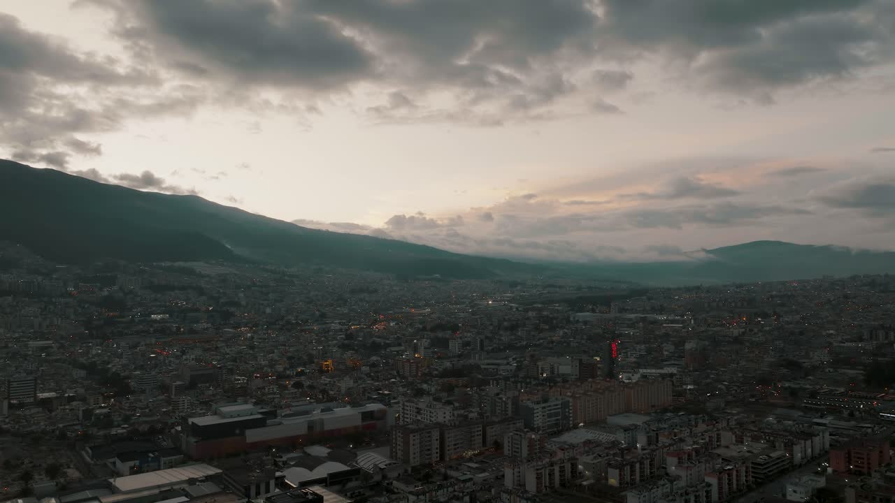 vuelo aéreo de drones que muestra las vibraciones del atardecer sobre la ciudad de quito y la silueta de la cordillera en el fondo