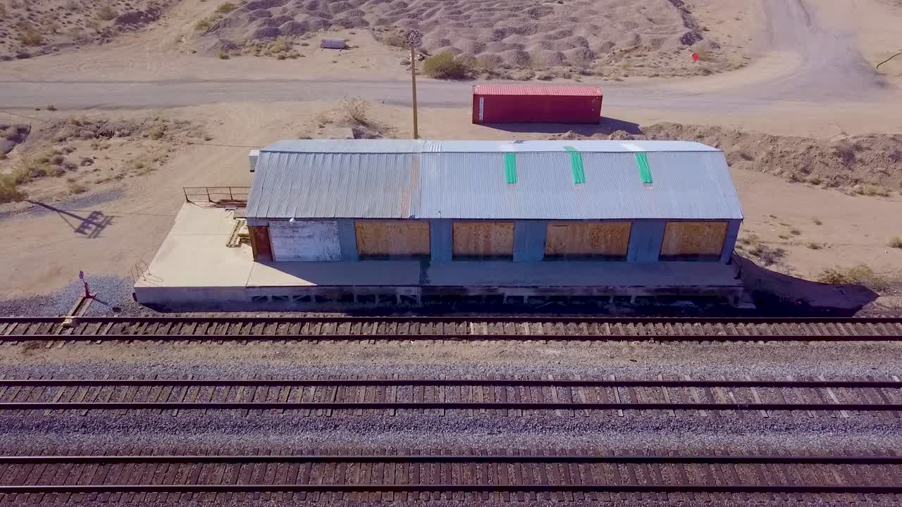 Aerial view backing away from abandoned railroad depot and tracks