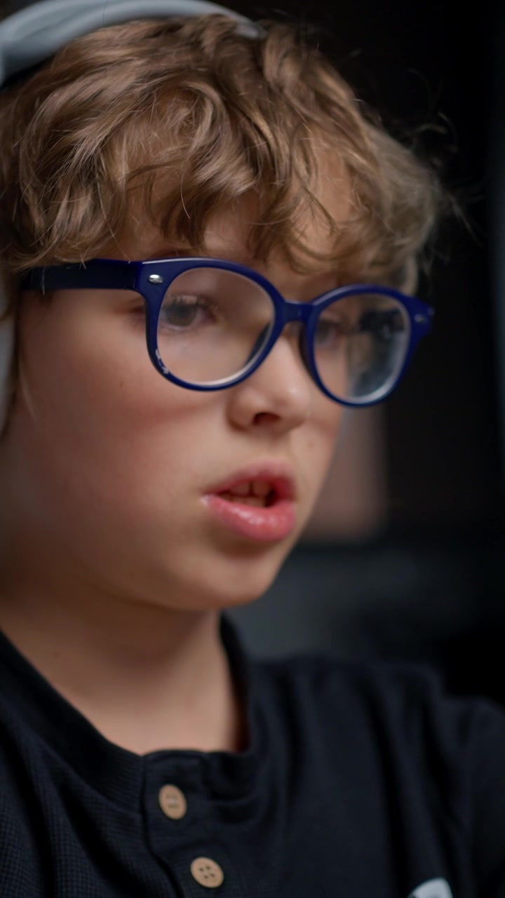 Giovane ragazzo concentrato con occhiali e cuffie che studia con tablet e penna