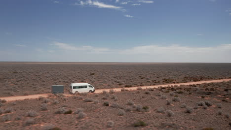 Vista-Aérea-Alrededor-De-Una-Furgoneta-Rv-Y-Un-Remolque,-Conduciendo-En-Un-Desierto-Interminable---Dando-Vueltas,-Tiro-De-Drones