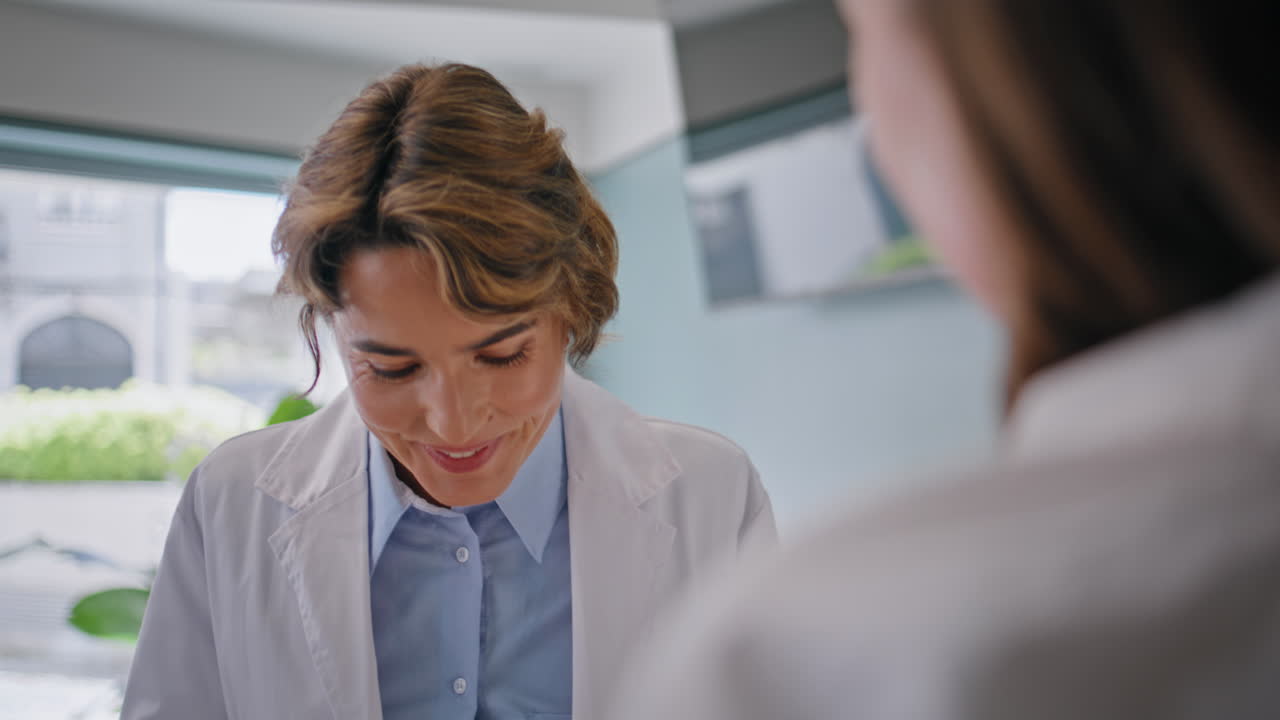 Smiling doctor talking colleague in medical office closeup. Woman professional