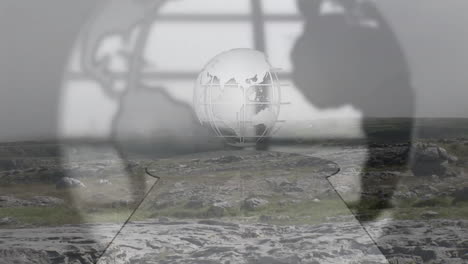 wireframe globe hovering above rocky plateau, blurred hand silhouettes framing keyhole cutout