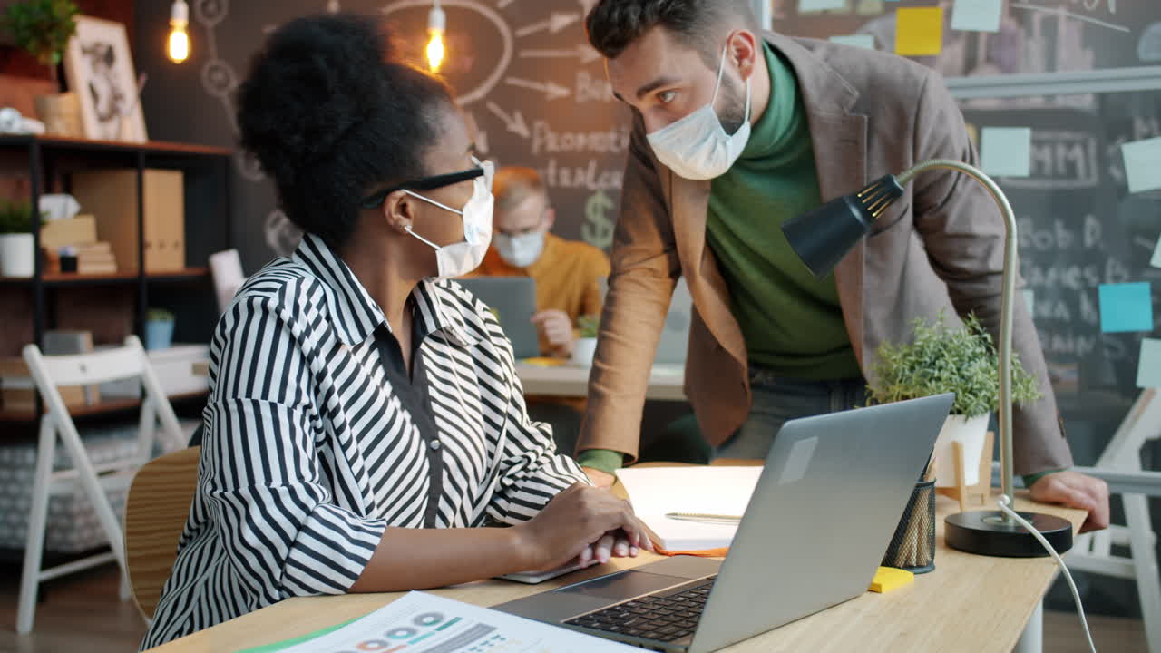 Business Colleagues Collaborating on a Laptop in a Modern Office Setting During Pandemic
