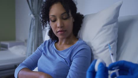 mixed race female patient sitting in hospital bed preparing to have injection