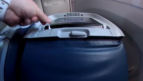 a hand plugs in white airline issued headphones into an entertainment screen on an airport chair