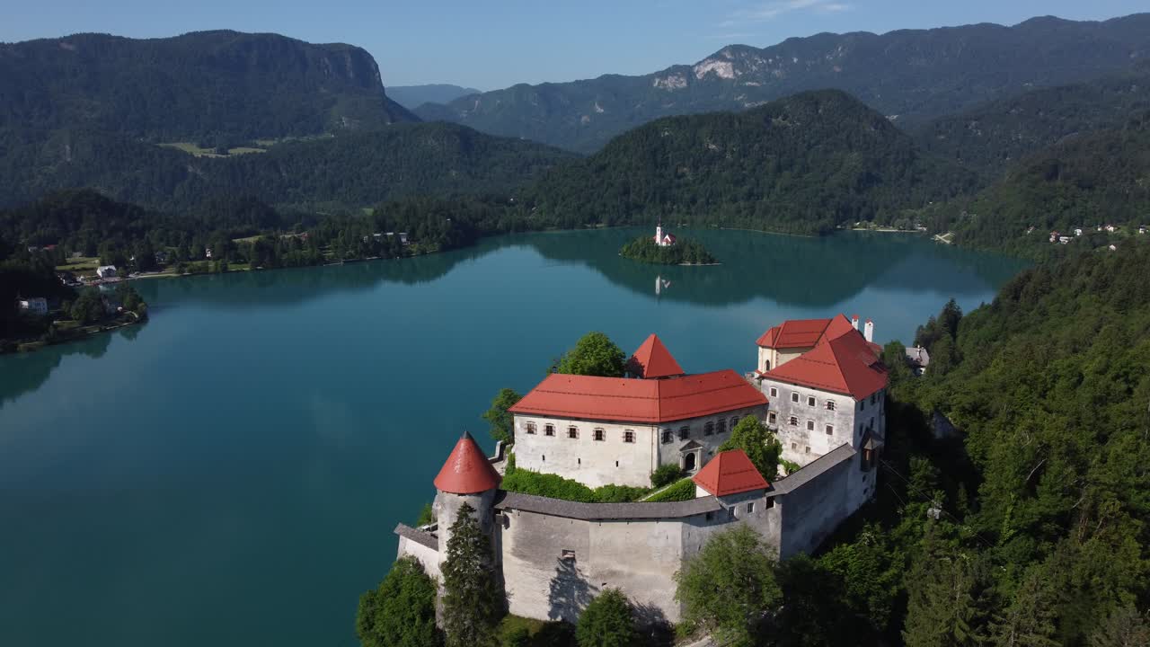 Panorama di lago glaciale alpino e castello con piccola isola. Filmato video stock di alta qualità 4K ripreso con drone.