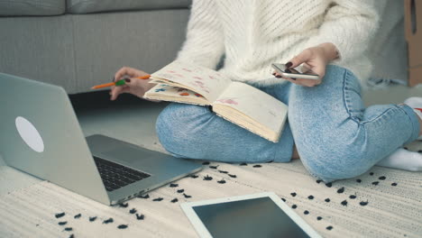 mujer joven artista que trabaja con ilustraciones, una computadora portátil y un teléfono inteligente