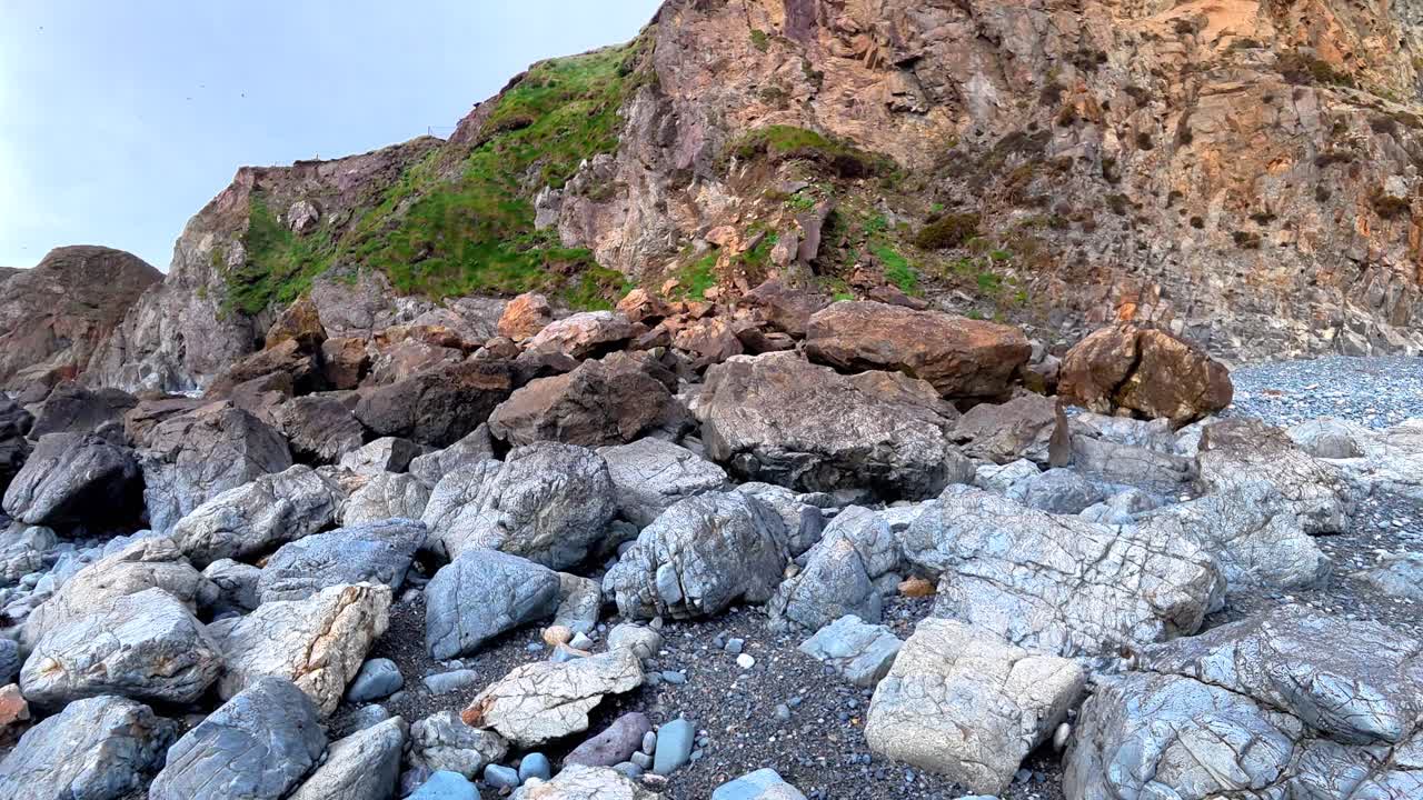 Panoramica verso l'alto di una frana costiera dopo una tempesta invernale e le alte maree, sulla costa di Waterford, Irlanda.