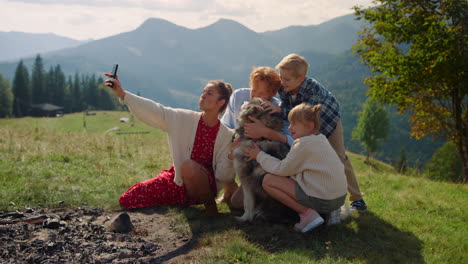 family taking selfie mountain hill sitting with husky. woman making happy photo.