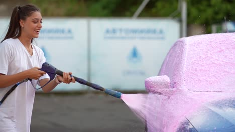 mujer lavando el coche con espuma rosa