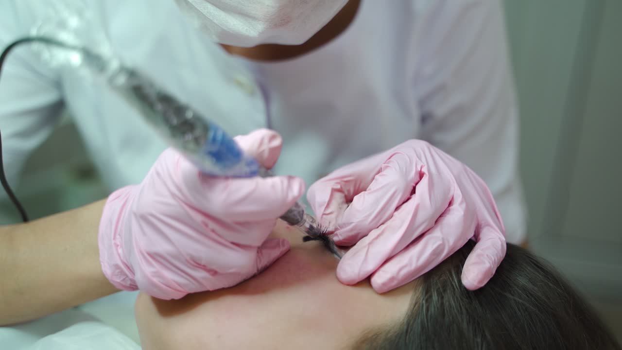 a beautician in gloves is working with the using of professional equipment in a beauty salon. The procedure of permanent makeup of eyes for women.