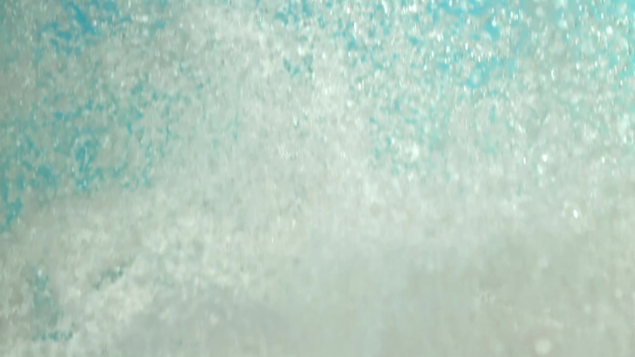 Primo piano astratto di particelle bianche che si dissolvono in un liquido turchese