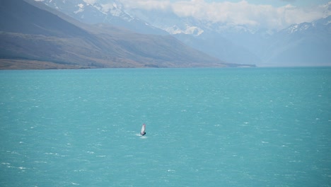 Windsurfista-En-El-Llamativo-Lago-Aguamarina,-Fondo-De-Montaña-Nevada