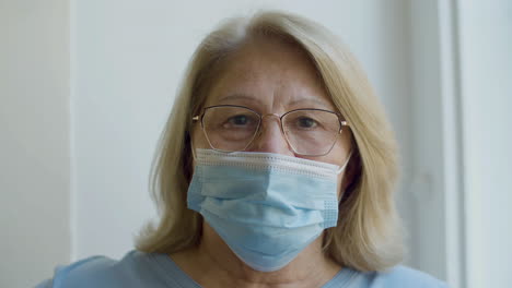 close-up shot of cute aged woman in face mask looking at camera