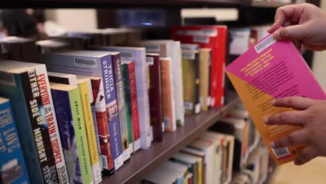 persona seleccionando un libro de la estantería de la biblioteca