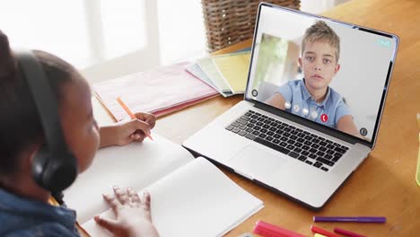 Composition-of-african-american-schoolgirl-on-laptop-online-learning-with-caucasian-schoolboy