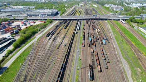 disparo aéreo escénico de un tren de pasajeros que conduce hacia el atardecer en vías de tren rodeadas de árboles por encima del paisaje urbano hacia adelante