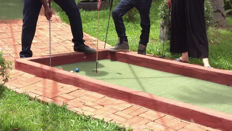 Jugadores-Divirtiéndose-Bajo-El-Sol-En-El-Campo-De-Minigolf