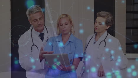 animation of blue glowing spots over team of medical health workers using digital tablet at hospital