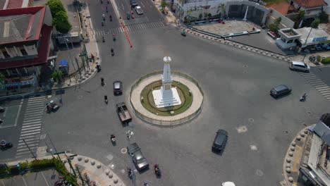 aerial orbiting shot of tugu yogyakarta with busy traffic on road in city during sunny day