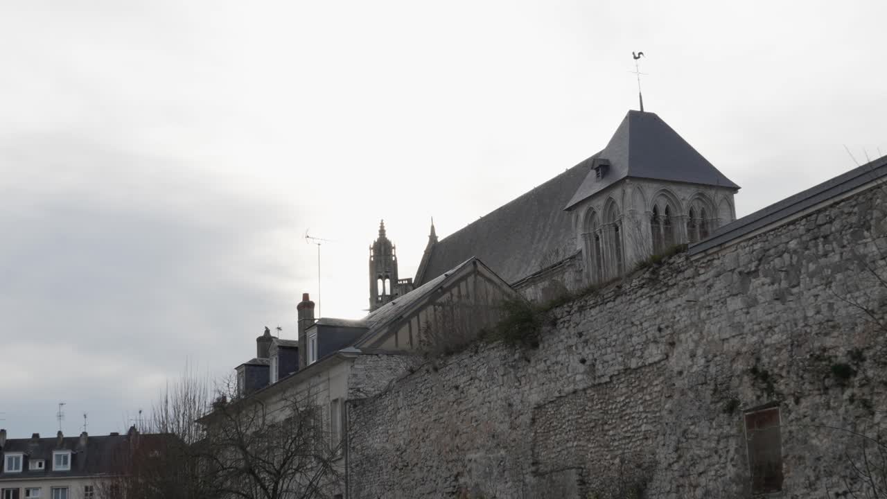 Side angle view of old weathered rock wall protecting large official buildings in vernon france