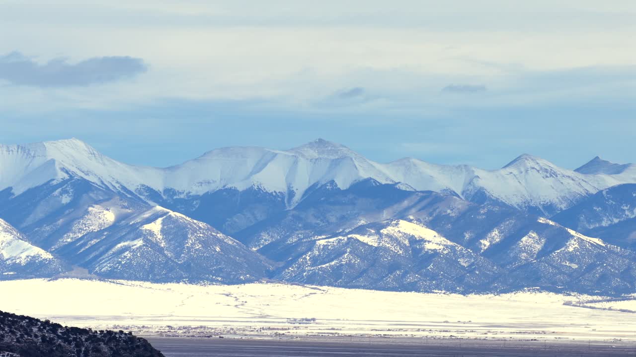 息を呑むような広大な景色。雪を頂いた巨大なサン・デ・クリスト山脈が、雪に覆われた広大なコロラド州の谷底からそびえ立っています。