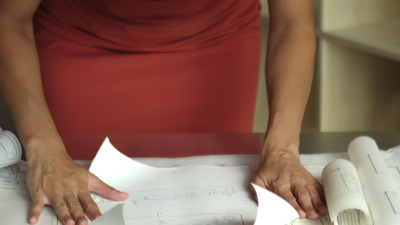 joven arquitecta mira rollos de planes de construcción