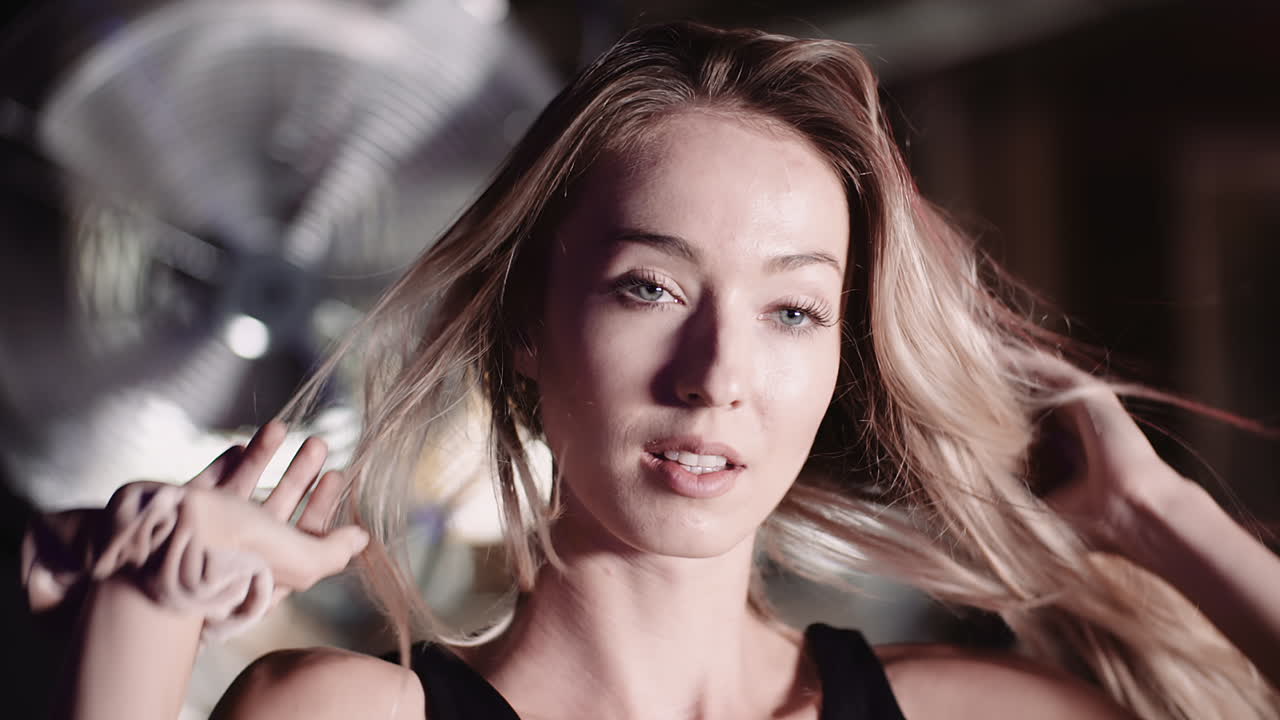 체육관 1에서 긴 머리를 통해 손을 움직이는 자신감 있는 젊은 여성의 슬로우 모션