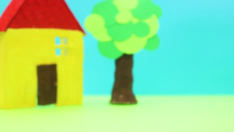 little red vintage car passing by yellow house and tree - stop motion