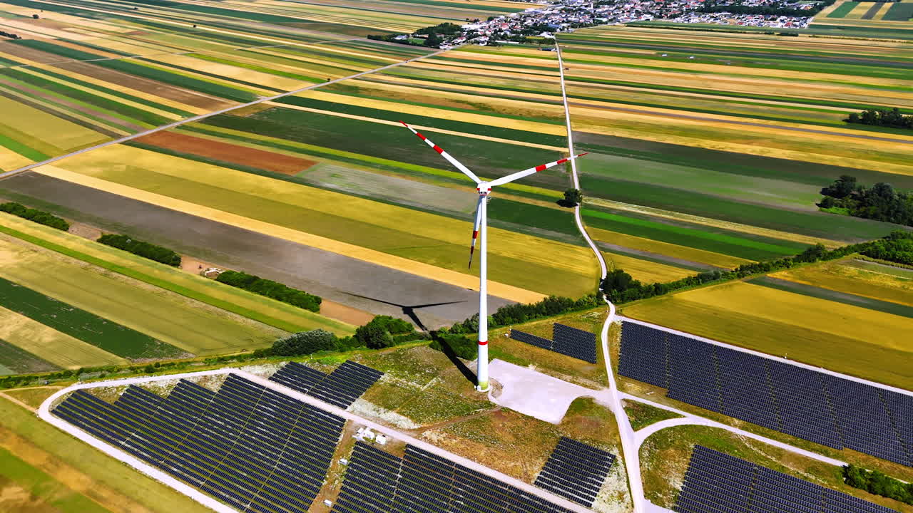 Wind and solar on farmland. A wind turbine stands next to solar panels on vibrant fields during daylight, showcasing renewable energy integration