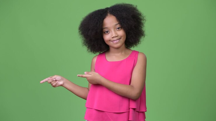 Giovane e carina ragazza africana con capelli afro che mostra qualcosa.