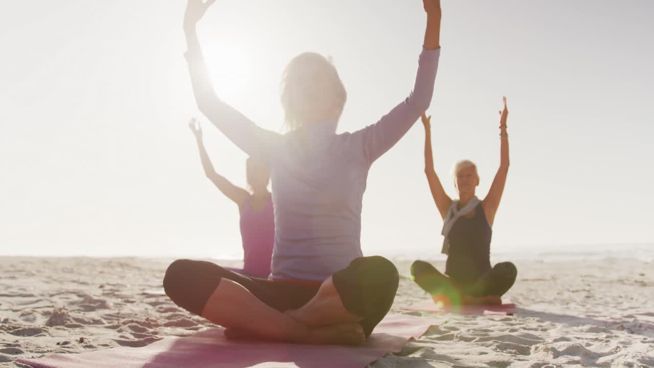 donne atletiche che fanno yoga sulla spiaggia
