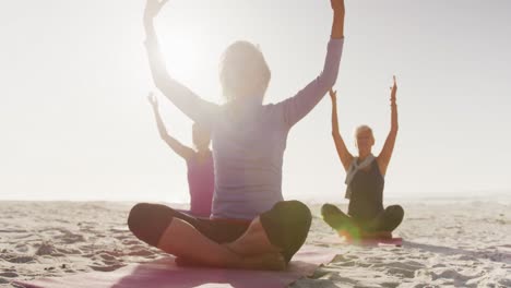 athletic women performing yoga in the beach