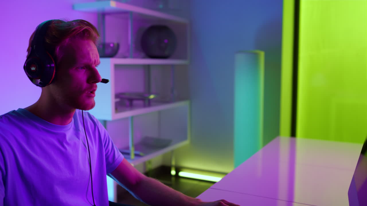 Cyber giocatore parla al microfono delle cuffie comunicando con la squadra in una stanza al neon, primo piano.