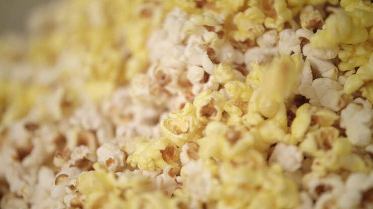 Popcorn pronti che cadono nella macchina per popcorn. Produzione di popcorn
